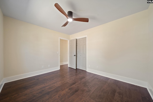 unfurnished room with dark wood-style floors, a ceiling fan, and baseboards