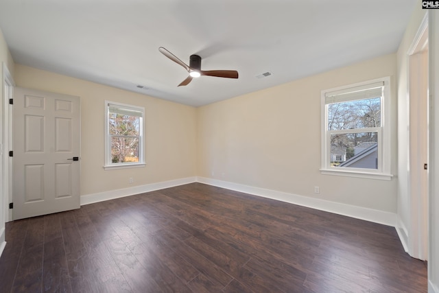 unfurnished bedroom with dark wood-type flooring, multiple windows, baseboards, and visible vents