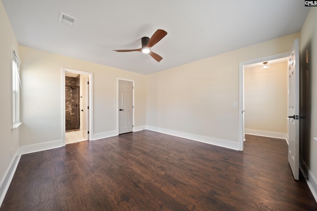 unfurnished bedroom featuring visible vents, connected bathroom, ceiling fan, baseboards, and dark wood finished floors