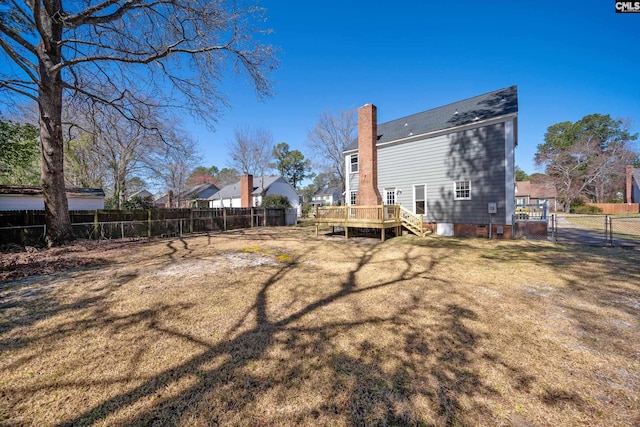 view of yard featuring a deck, a fenced backyard, and a gate