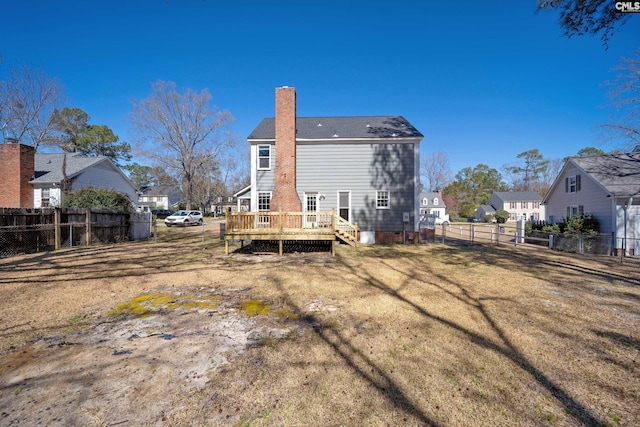 back of house with a wooden deck, a lawn, a fenced backyard, and a chimney