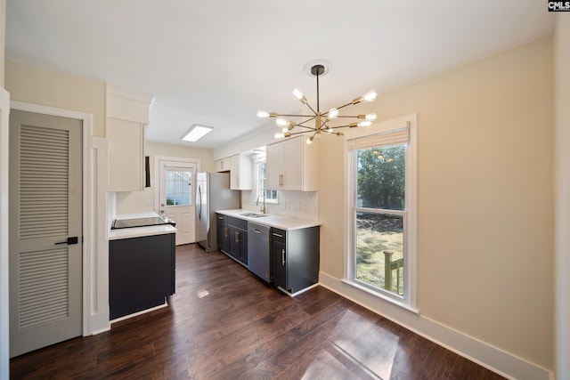 kitchen with dark wood finished floors, white cabinetry, appliances with stainless steel finishes, light countertops, and a chandelier