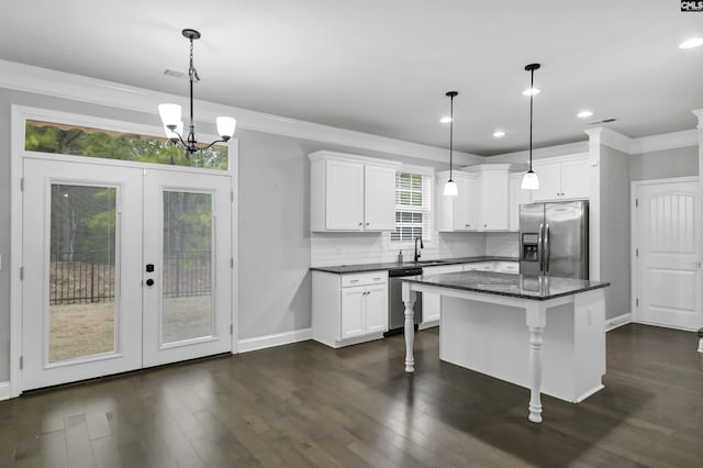 kitchen with backsplash, crown molding, dark wood finished floors, appliances with stainless steel finishes, and white cabinetry