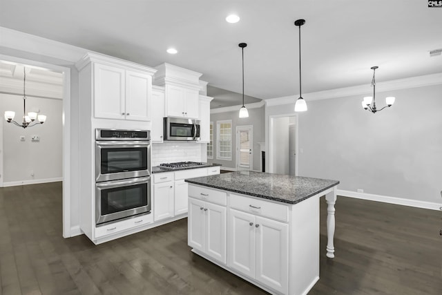 kitchen with a notable chandelier, a kitchen island, backsplash, appliances with stainless steel finishes, and crown molding