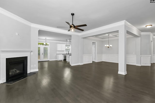 unfurnished living room featuring dark wood-type flooring, ceiling fan with notable chandelier, a glass covered fireplace, crown molding, and a decorative wall