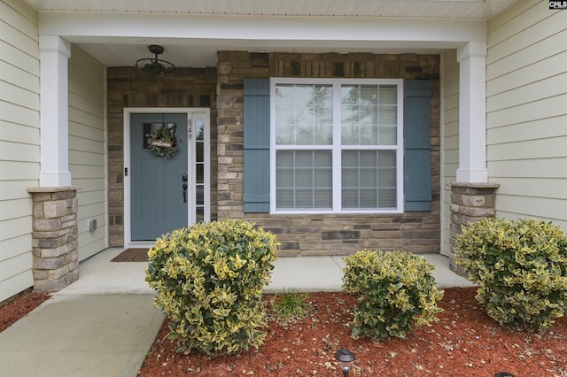 entrance to property with stone siding and a porch