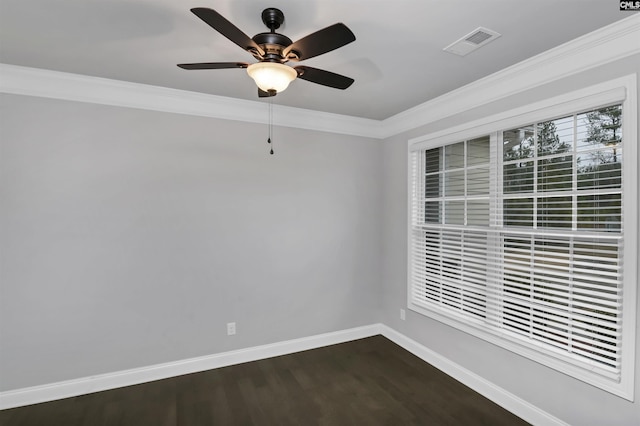 spare room with visible vents, dark wood-type flooring, a ceiling fan, crown molding, and baseboards