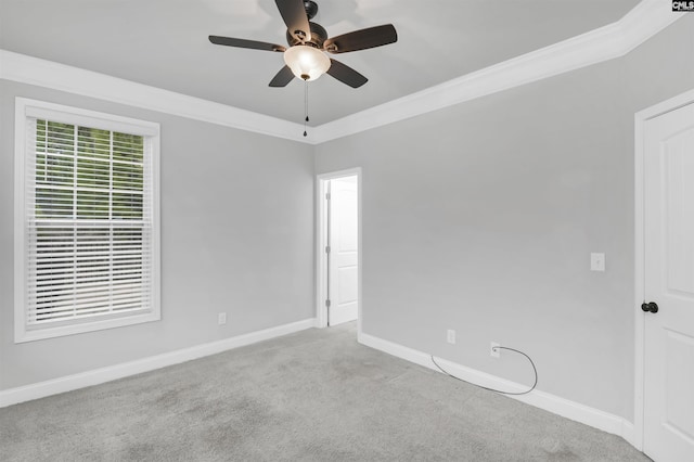 carpeted empty room with ceiling fan, crown molding, and baseboards