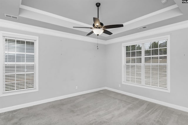 carpeted spare room featuring a tray ceiling, crown molding, visible vents, and baseboards