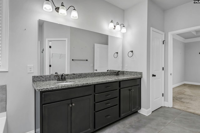 full bath featuring a sink, a walk in closet, baseboards, and double vanity