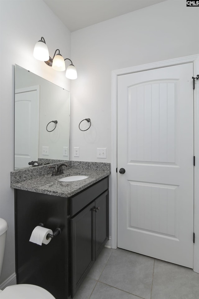 bathroom with toilet, vanity, and tile patterned flooring