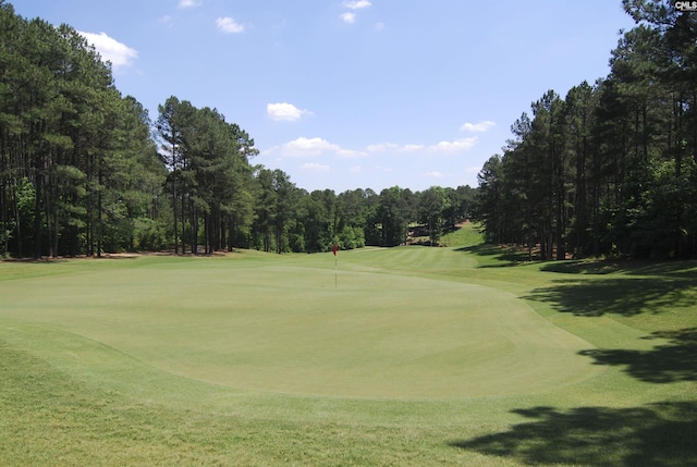 view of property's community featuring view of golf course and a lawn