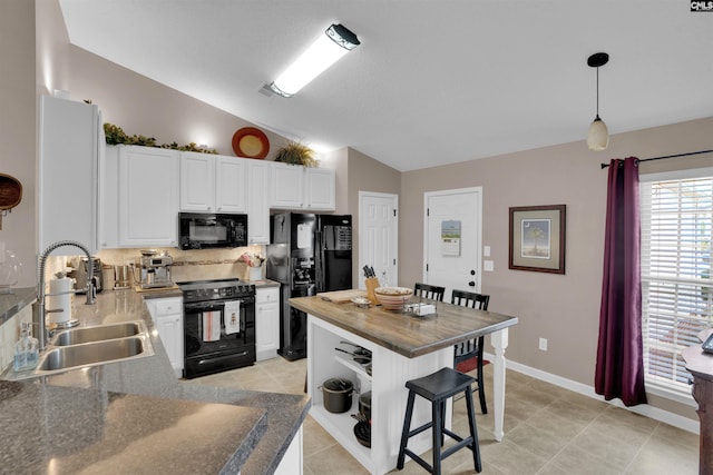 kitchen featuring a kitchen bar, vaulted ceiling, decorative backsplash, black appliances, and a sink