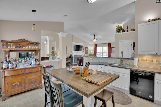 kitchen featuring dishwasher, a fireplace, a peninsula, white cabinets, and a sink