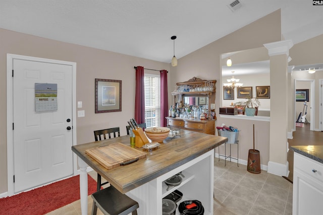 dining area with visible vents, a chandelier, lofted ceiling, decorative columns, and light tile patterned floors