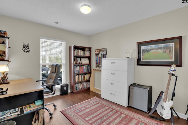 office featuring a textured ceiling, baseboards, and wood finished floors