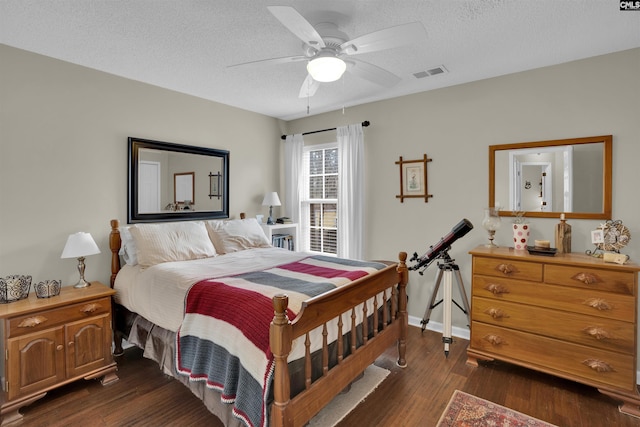 bedroom featuring visible vents, dark wood-type flooring, baseboards, ceiling fan, and a textured ceiling