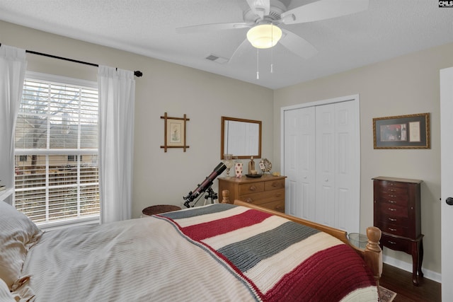 bedroom with visible vents, wood finished floors, a closet, a textured ceiling, and a ceiling fan