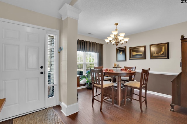 dining area featuring decorative columns, baseboards, dark wood-type flooring, and a chandelier