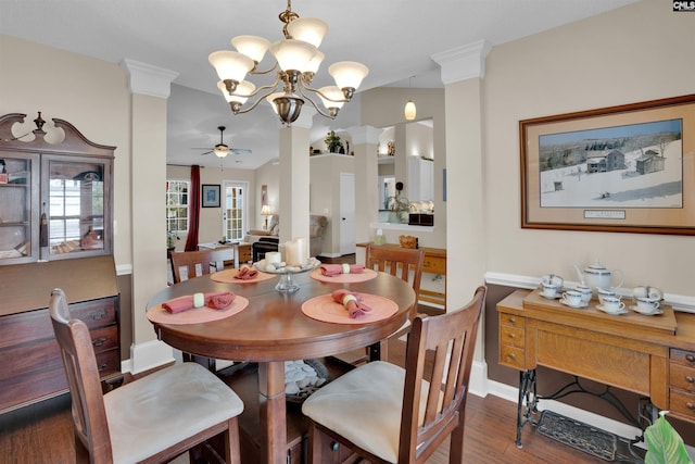 dining space featuring ceiling fan with notable chandelier, wood finished floors, baseboards, and decorative columns