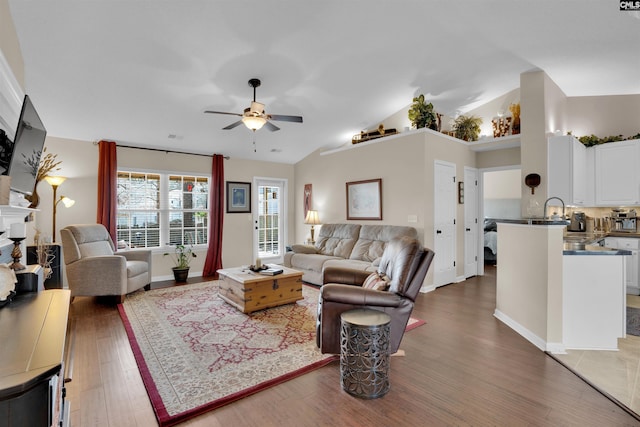 living room featuring visible vents, baseboards, ceiling fan, vaulted ceiling, and wood finished floors