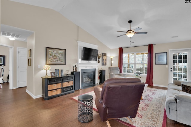 living area featuring visible vents, a fireplace with flush hearth, wood finished floors, lofted ceiling, and ceiling fan