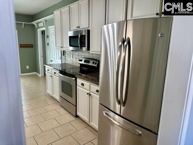 kitchen featuring light tile patterned floors, stainless steel appliances, white cabinets, and decorative backsplash