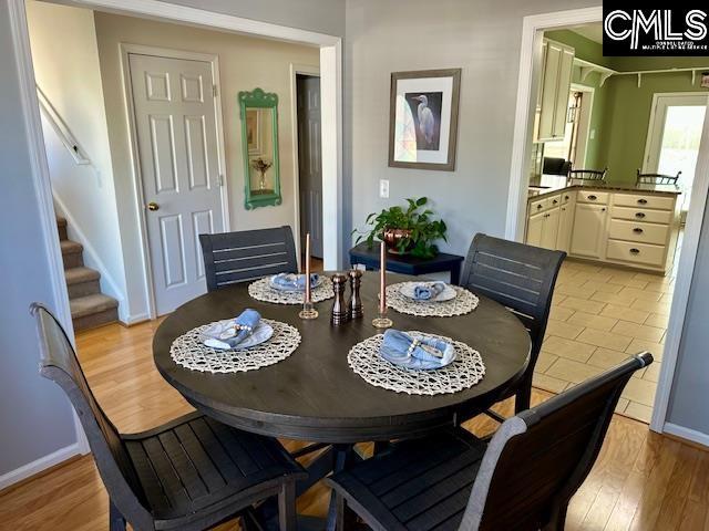 dining area featuring baseboards, stairs, and light wood finished floors