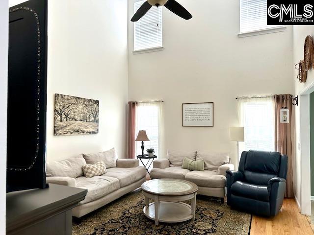 living area with plenty of natural light, a high ceiling, and light wood finished floors