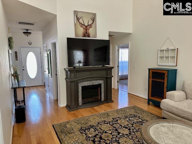 living area featuring light wood-style flooring, a fireplace, and visible vents