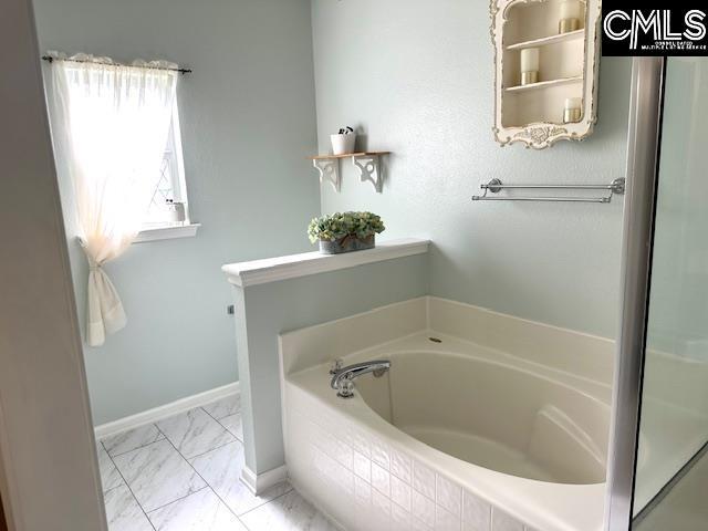 bathroom featuring baseboards, marble finish floor, and a bath