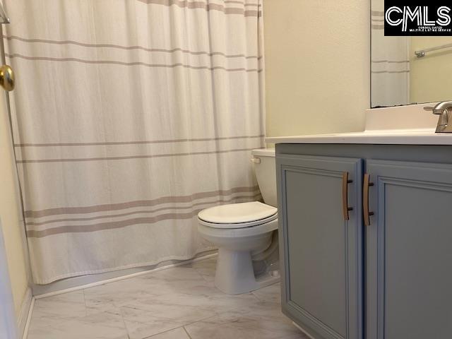 full bath with a shower with curtain, toilet, marble finish floor, and vanity