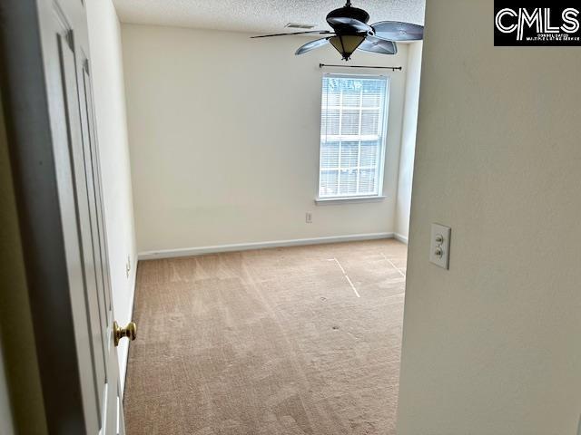 unfurnished room with carpet, a ceiling fan, baseboards, and a textured ceiling