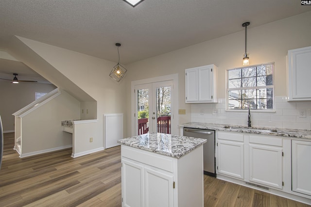 kitchen featuring tasteful backsplash, visible vents, dishwasher, white cabinetry, and a sink