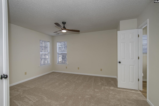 empty room featuring carpet flooring, a ceiling fan, baseboards, and a textured ceiling