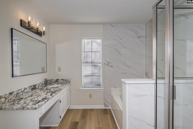 full bath with a stall shower, a textured ceiling, vanity, and wood finished floors