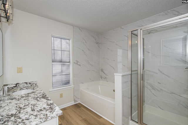 full bath with a marble finish shower, vanity, a garden tub, wood finished floors, and a textured ceiling