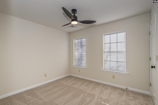 unfurnished room featuring a ceiling fan, visible vents, baseboards, a textured ceiling, and light carpet