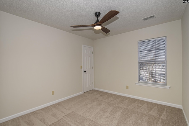 spare room with visible vents, baseboards, ceiling fan, a textured ceiling, and light colored carpet