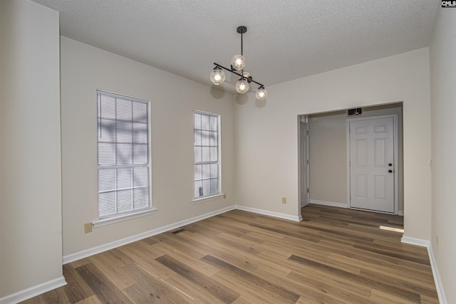 spare room with baseboards, a textured ceiling, and wood finished floors