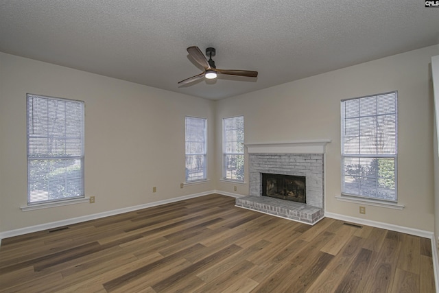 unfurnished living room featuring ceiling fan, a healthy amount of sunlight, wood finished floors, and a fireplace