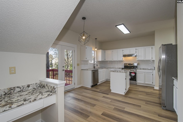 kitchen with wood finished floors, decorative backsplash, french doors, under cabinet range hood, and appliances with stainless steel finishes