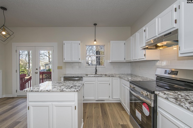 kitchen with wood finished floors, a sink, stainless steel appliances, under cabinet range hood, and white cabinetry