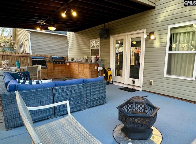 view of patio / terrace with area for grilling, an outdoor living space with a fire pit, exterior kitchen, and fence