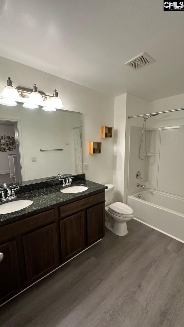 bathroom with shower / tub combination, wood finished floors, visible vents, and a sink