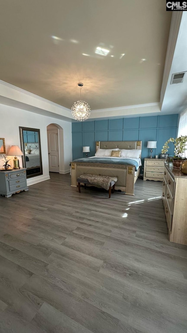 bedroom with arched walkways, visible vents, an inviting chandelier, and dark wood-style flooring