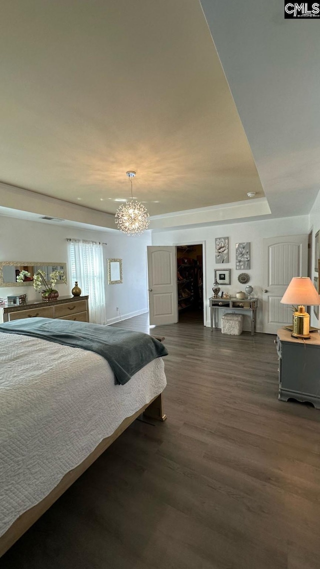 bedroom with a tray ceiling and wood finished floors