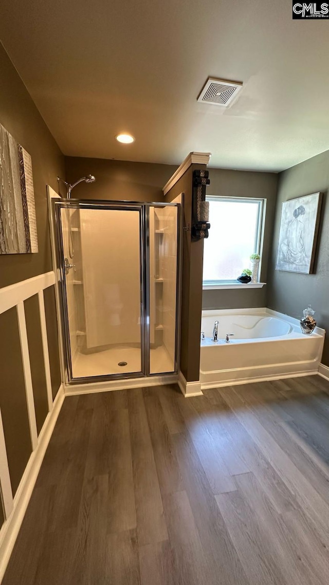 bathroom featuring a bath, visible vents, a shower stall, and wood finished floors