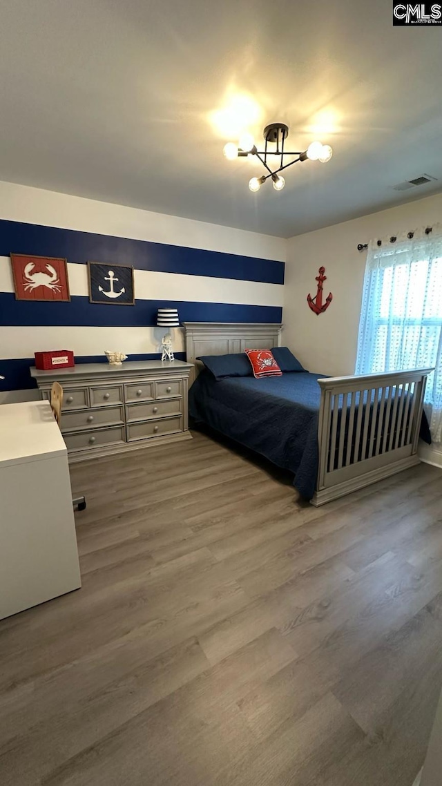 bedroom featuring a chandelier, visible vents, and wood finished floors