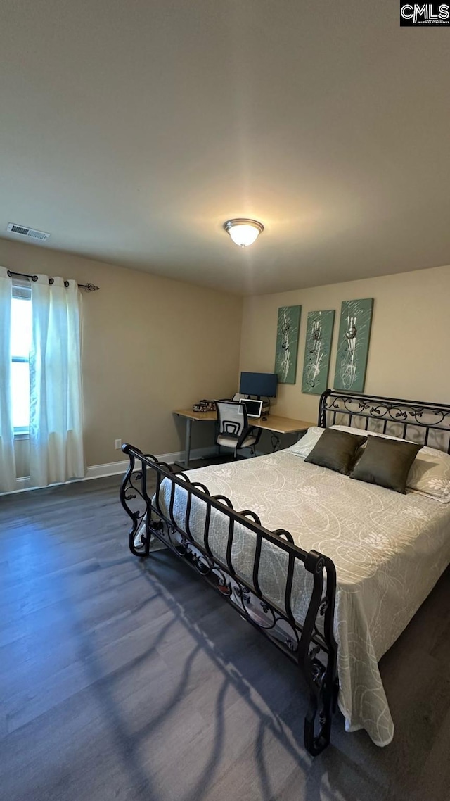 bedroom with visible vents, baseboards, and wood finished floors